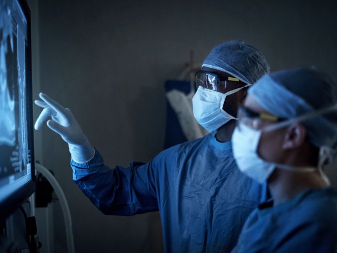 Aufnahme von zwei Chirurgen, die während der Operation medizinische Scans eines Patienten analysieren