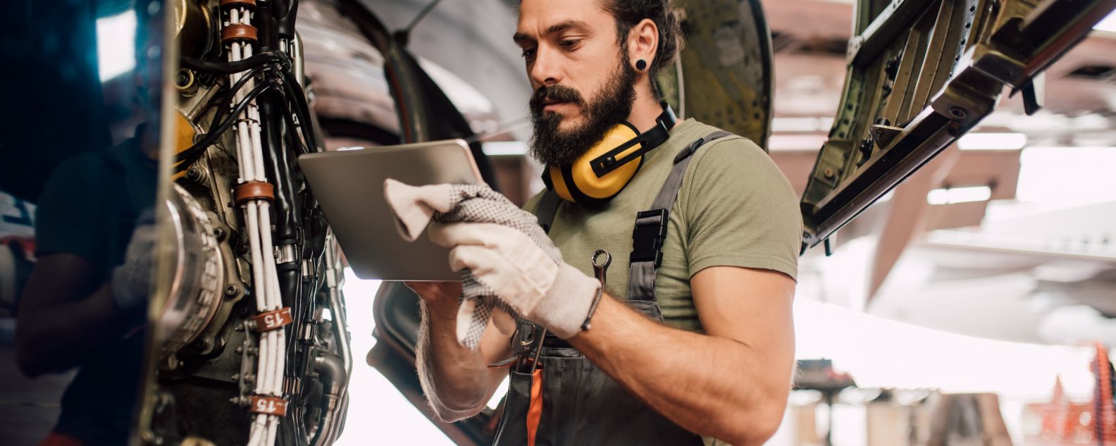 Un hombre usando una tableta digital al reparar un avión