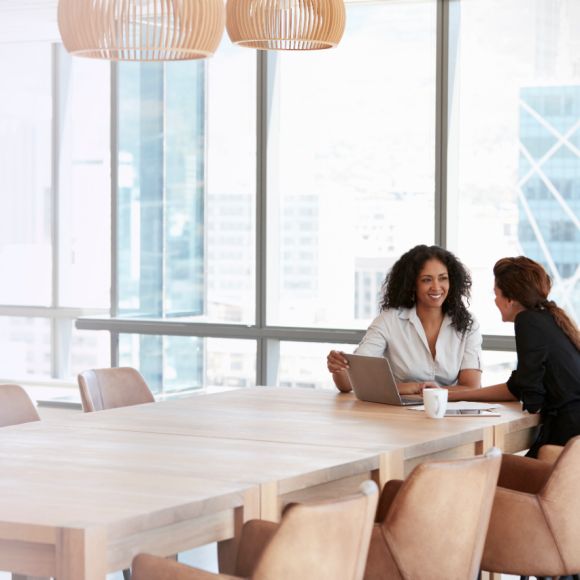 Dos mujeres de negocios utilizando un portátil en una reunión en la sala de juntas