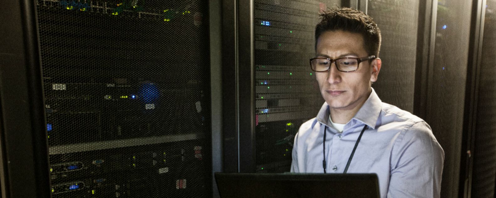 Technicien hispanique effectuant des tests de diagnostic sur des serveurs informatiques