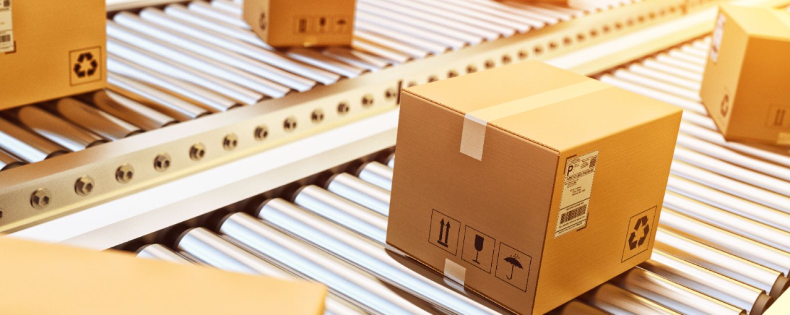 Cajas de cartón sobre una cinta transportadora en una línea de embalaje de un almacén de distribución