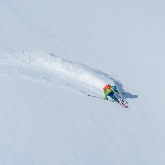 Pemain ski menuruni lereng salju halus di pegunungan