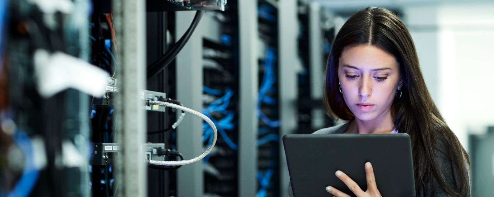 a woman looking at a tablet in a server room