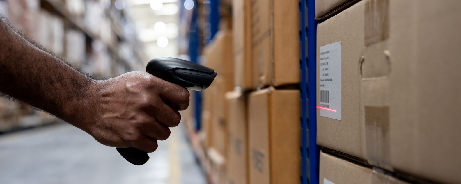 A hand scans packages in a warehouse