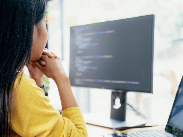 Programmatore seduto al computer che osserva il codice