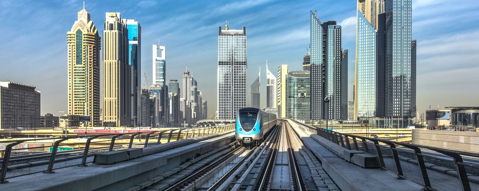 Driverless metro in Dubai approaching the subway station with futuristic city skyline on background in Dubai, United Arab Emirates, Persian Gulf.
