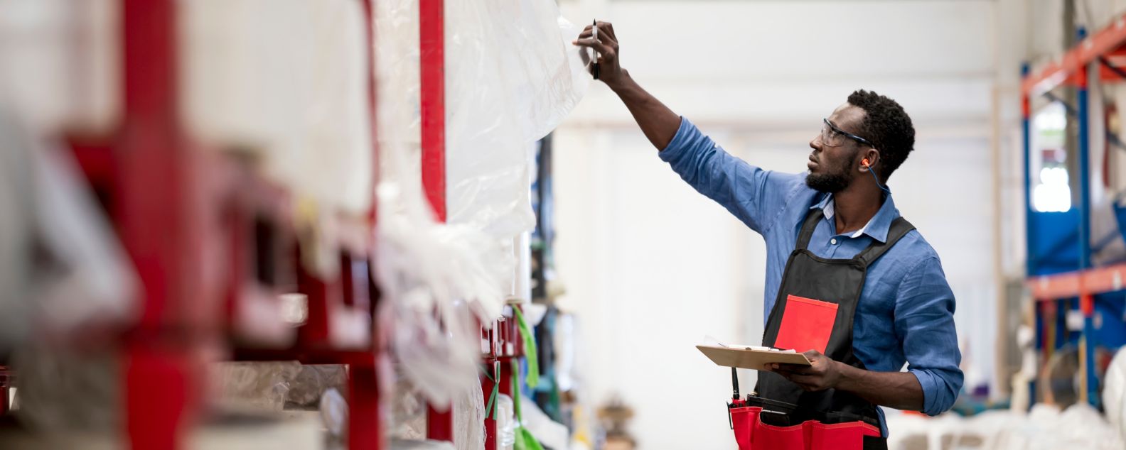 African American warehouse worker preparation or checking min max of raw materials stock balance for the production process in material warehouse.