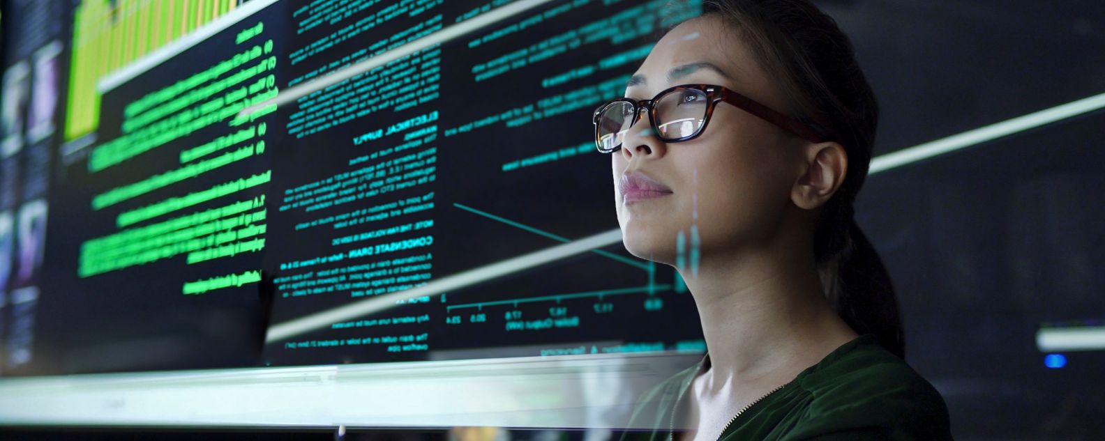 young Asian woman looking at see through data whilst seated in a dark office
