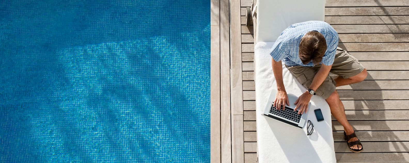 pessoa usando um notebook e um smartphone à beira da piscina