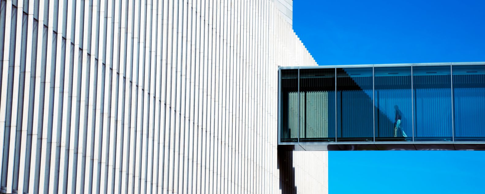 A person strolls through a modern building's skywalk