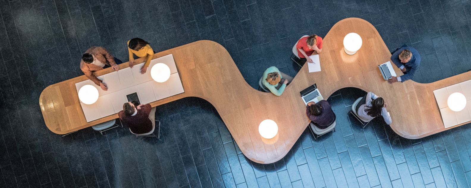 Overhead view of employees sitting at large zigzag meeting table