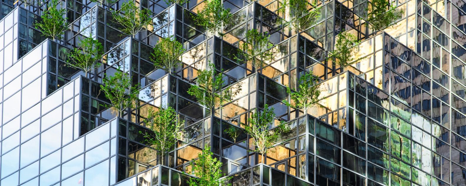 High angle view of a mirrored skyscraper with a modern trees installation on the facade