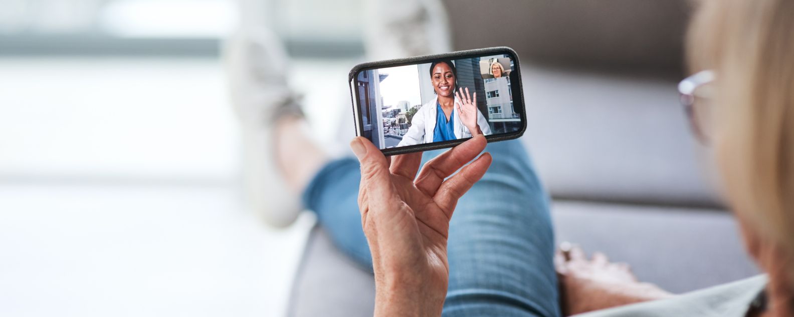 Shot of a senior woman using a smartphone to make a video call with her doctor on the sofa a home