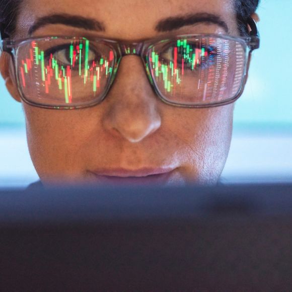 眼鏡に映る金融株式市場を分析する女性
