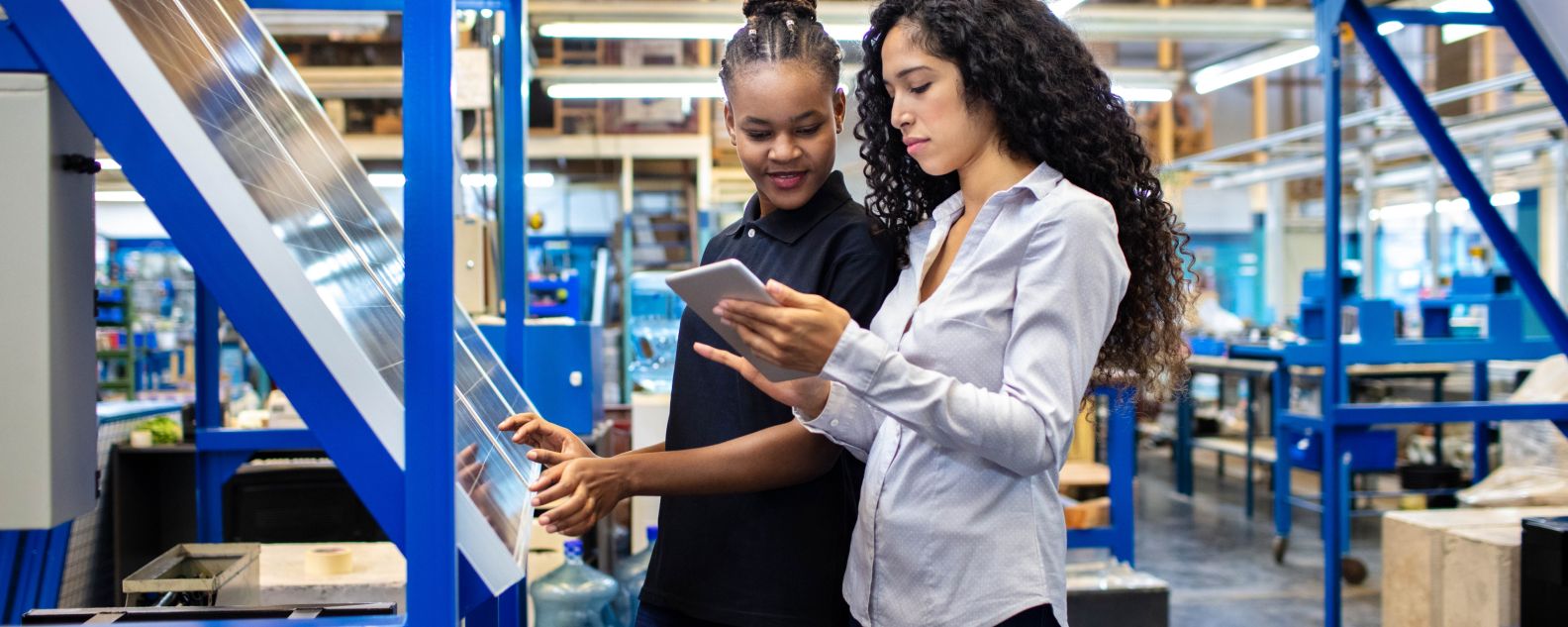 Supervisor dan pekerja wanita melihat tablet digital di lantai toko pabrik