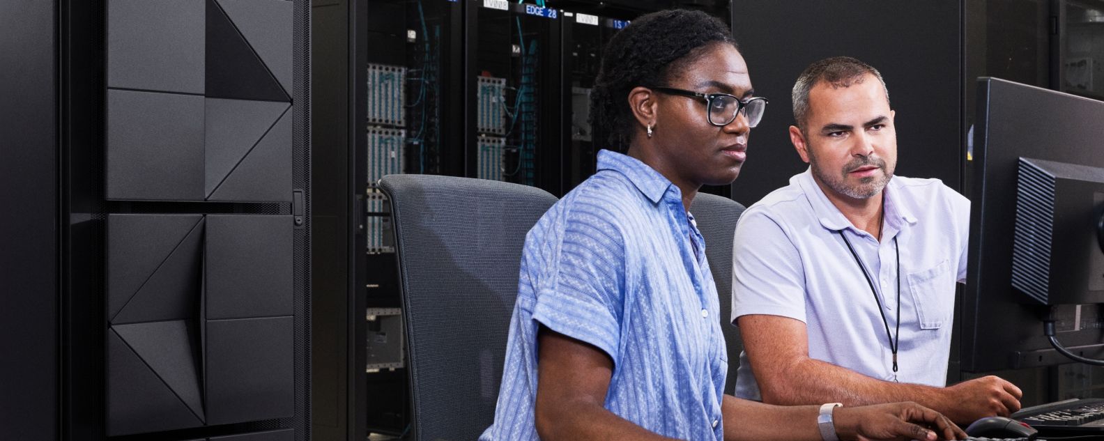 Dos ingenieros que trabajan en computadoras en la sala de servidores