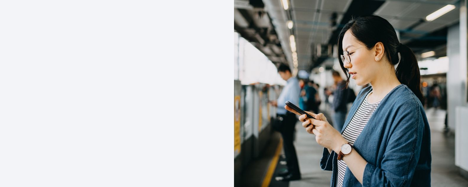 a commuter at a train station looks into a smartphone