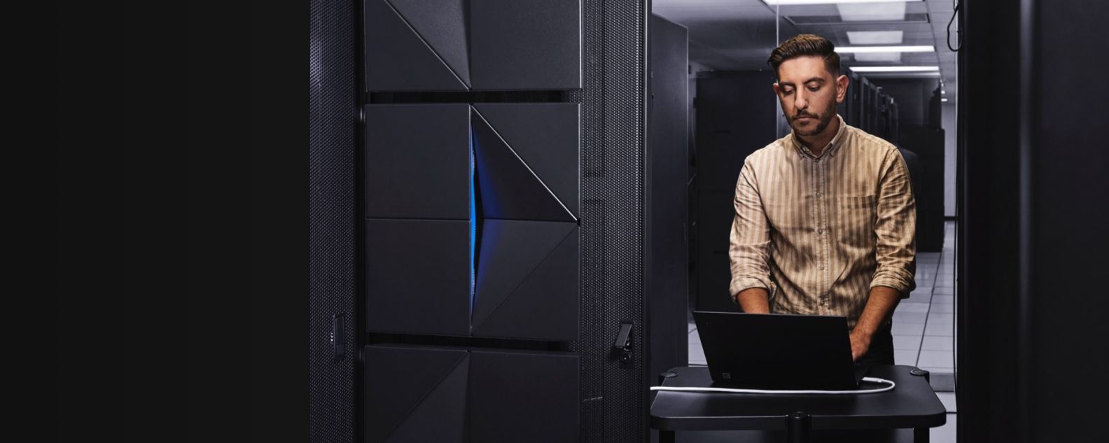 Sala de servidores mainframe com uma pessoa no computador