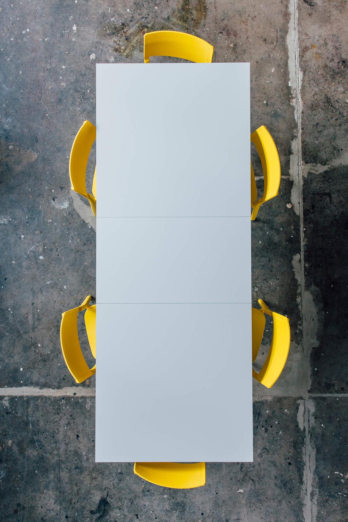 Top view of six yellow chairs on a bright gray table