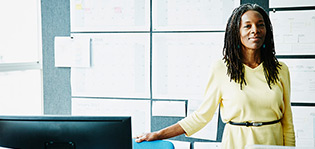Smiling businesswoman standing at workstation in office
