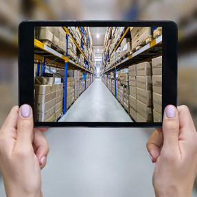 Hands holding tablet screen showing warehouse