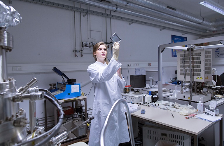 Woman in a lab standing and looking at a sample.