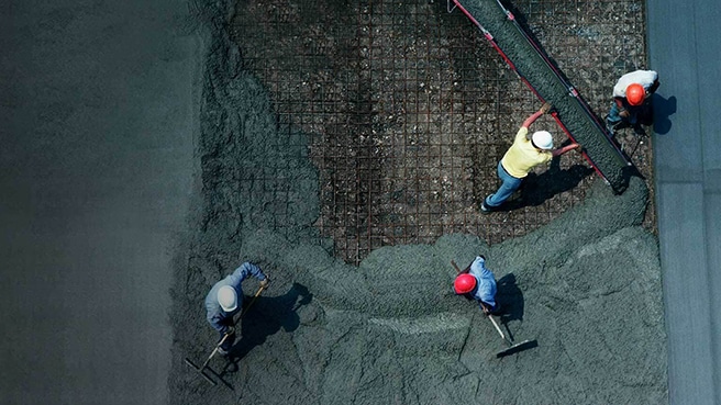 Overhead view of three workers pouring and leveling concrete