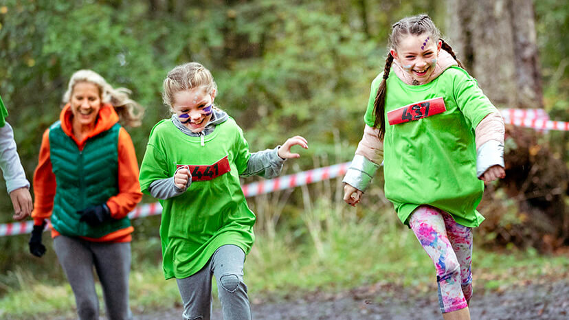 Two young sisters, bundled up in the cold and sporting face paint, compete in a fun run as their parents try and keep pace