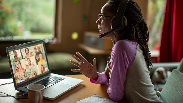 Woman with headphones on video conference call on laptop at home